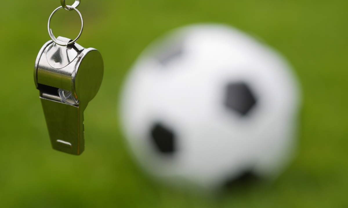 Fischietto da arbitro e pallone sullo sfondo